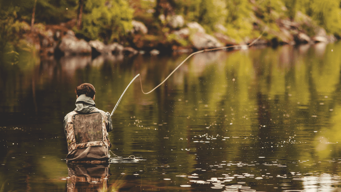 Man with his back to us fly casting in a lake