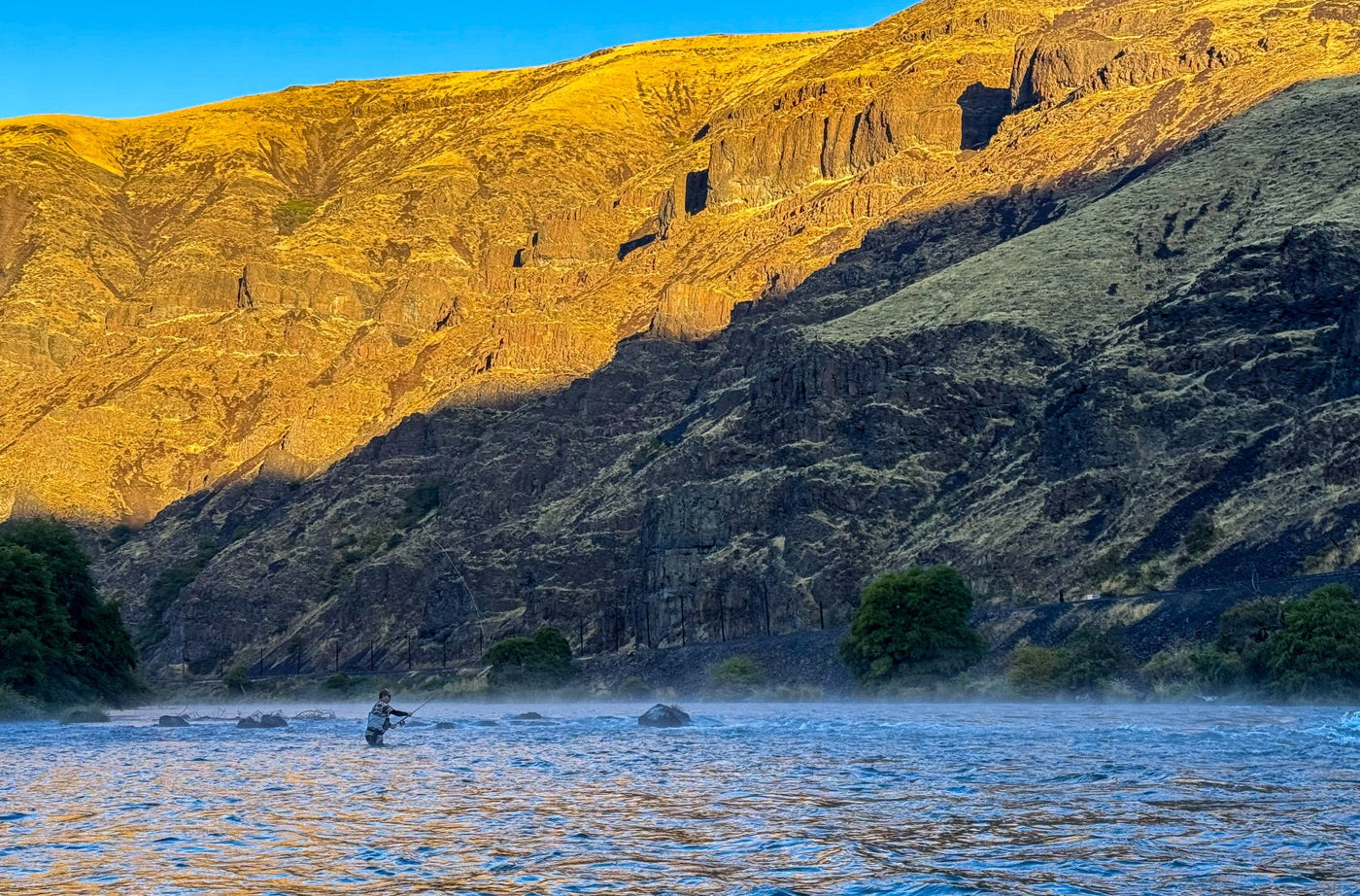 Man in waders fishing a two-handed spey rod in a Westen US river canyon.